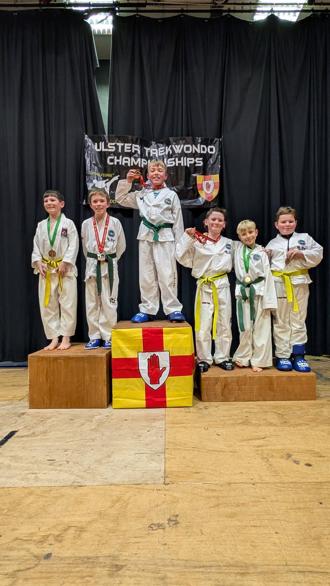 Junior Taekwon-Do students standing on a medal podium