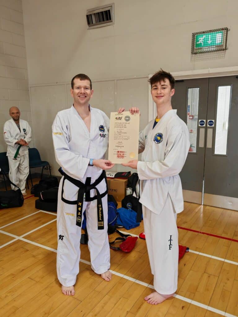 Student receiving Taekwon-Do grading certificate from instructor